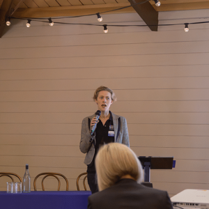 Woman addressing audience with microphone.